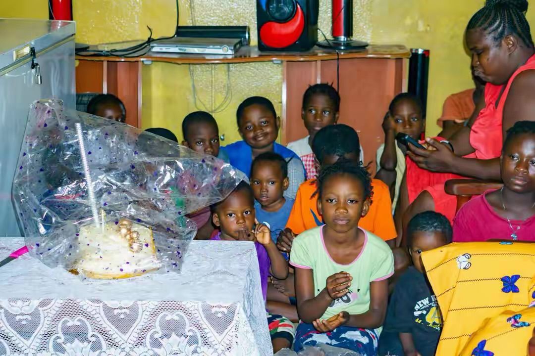 Children celebrate around a cake with gift packs